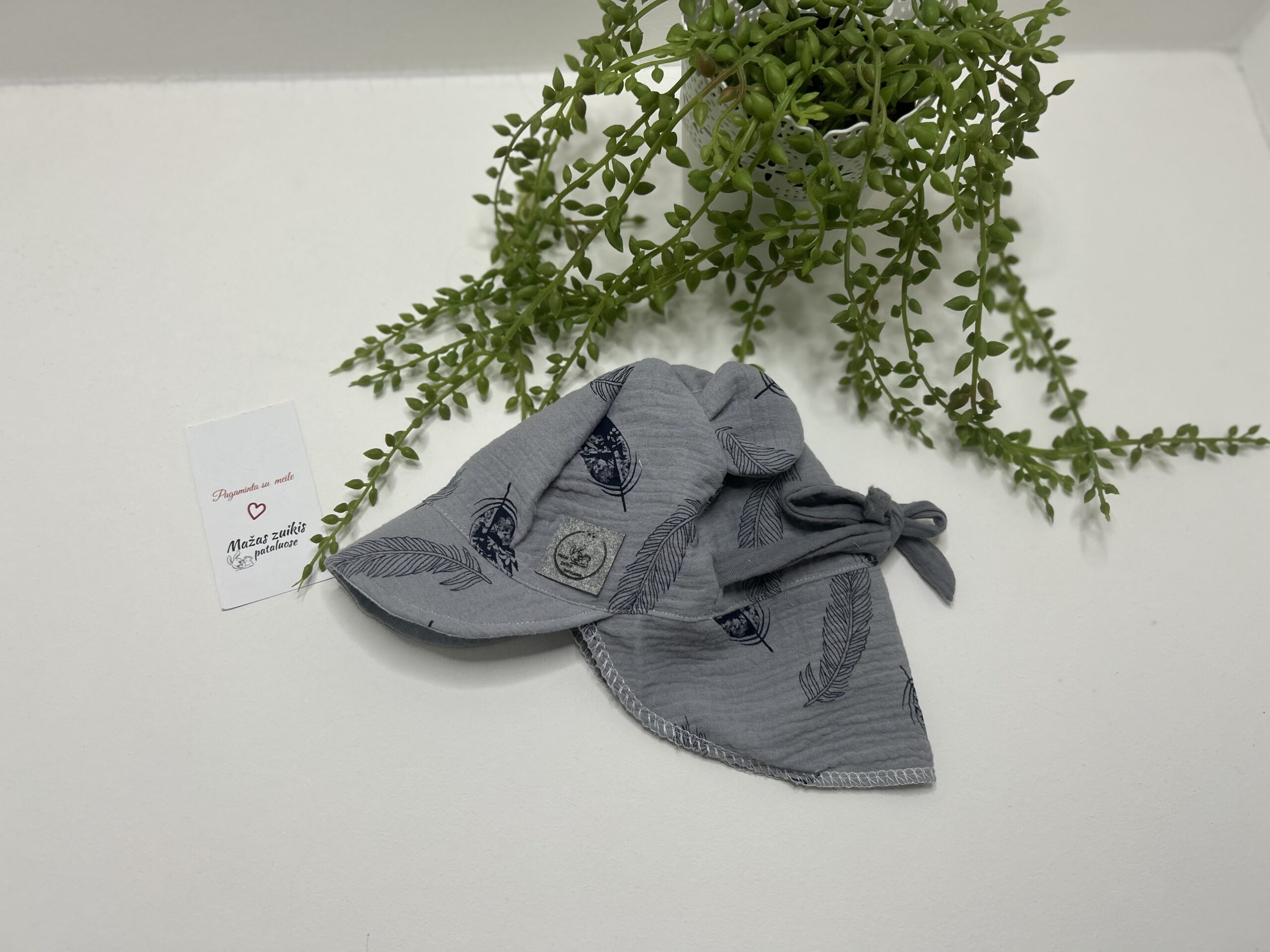 Muslino kepurė su snapeliu ir kaklo apsauga 3-6mėn “plunksnos pilkame fone”